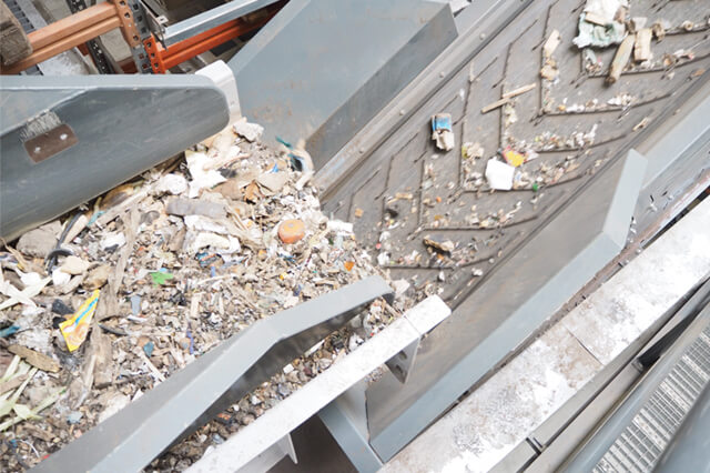 Detailbild eines Aufgabebunkers der Baumischabfaelle an ein Foerderband hin zu einer SPALECK Siebmaschine abgibt