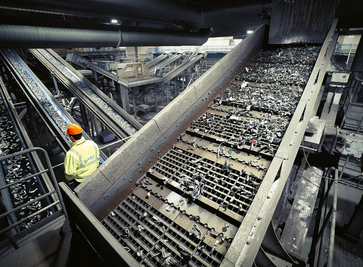A worker monitors a conveyor belt at a recycling plant.