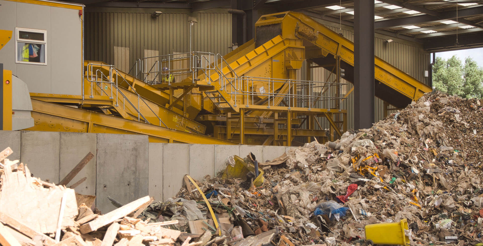 Recycling plant for mixed construction waste with conveyor belts and piles of waste.