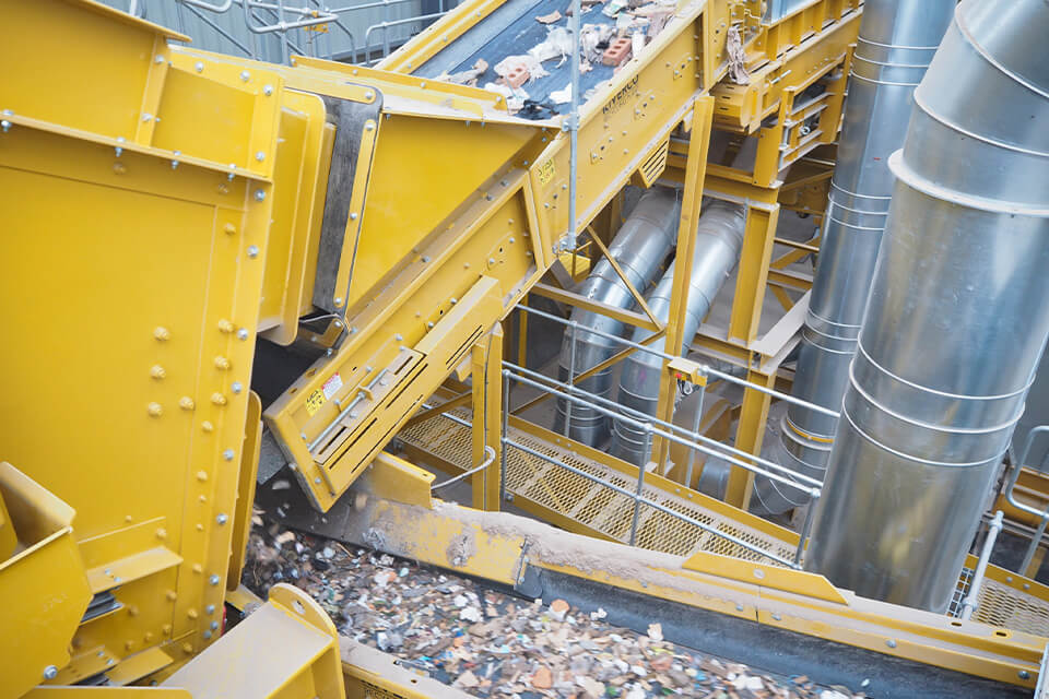 Yellow recycling plant for mixed construction waste with a conveyor belt.