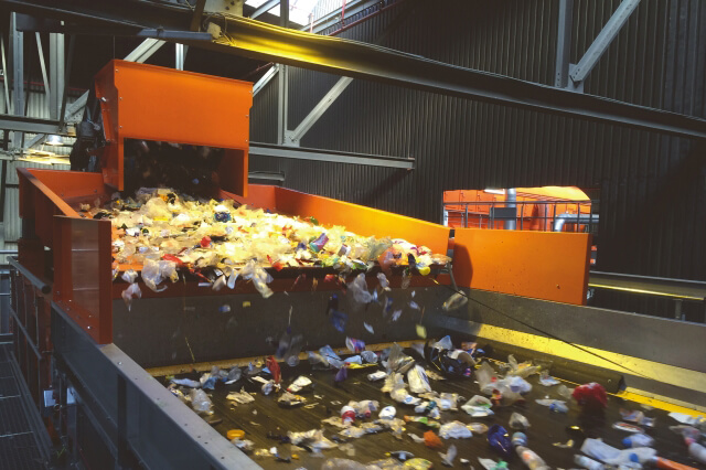 A vibrating conveyor chutes the recycled lightweight packaging material into an NIR sorting machine. The material is distributed evenly across the entire width, ensuring an optimal supply.
