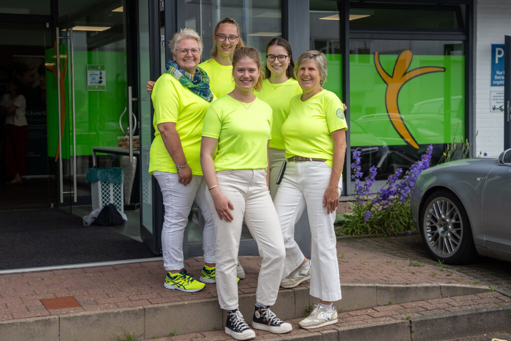Five people in yellow T-shirts in front of a building.