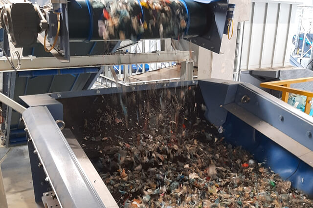 Material falls from a conveyor belt into a tension-shaft screen.