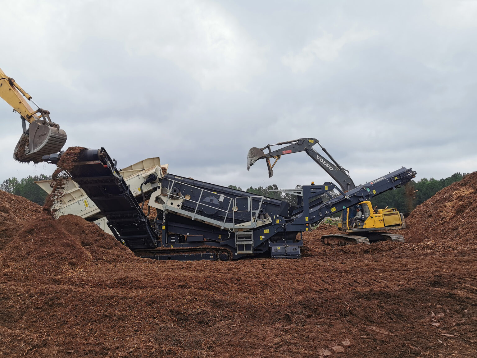 Mobile screening plants in use for material processing at a construction site.