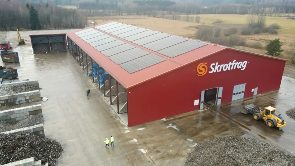 Skrotfrag recycling plant for non-ferrous metals, featuring a red building and solar panels.