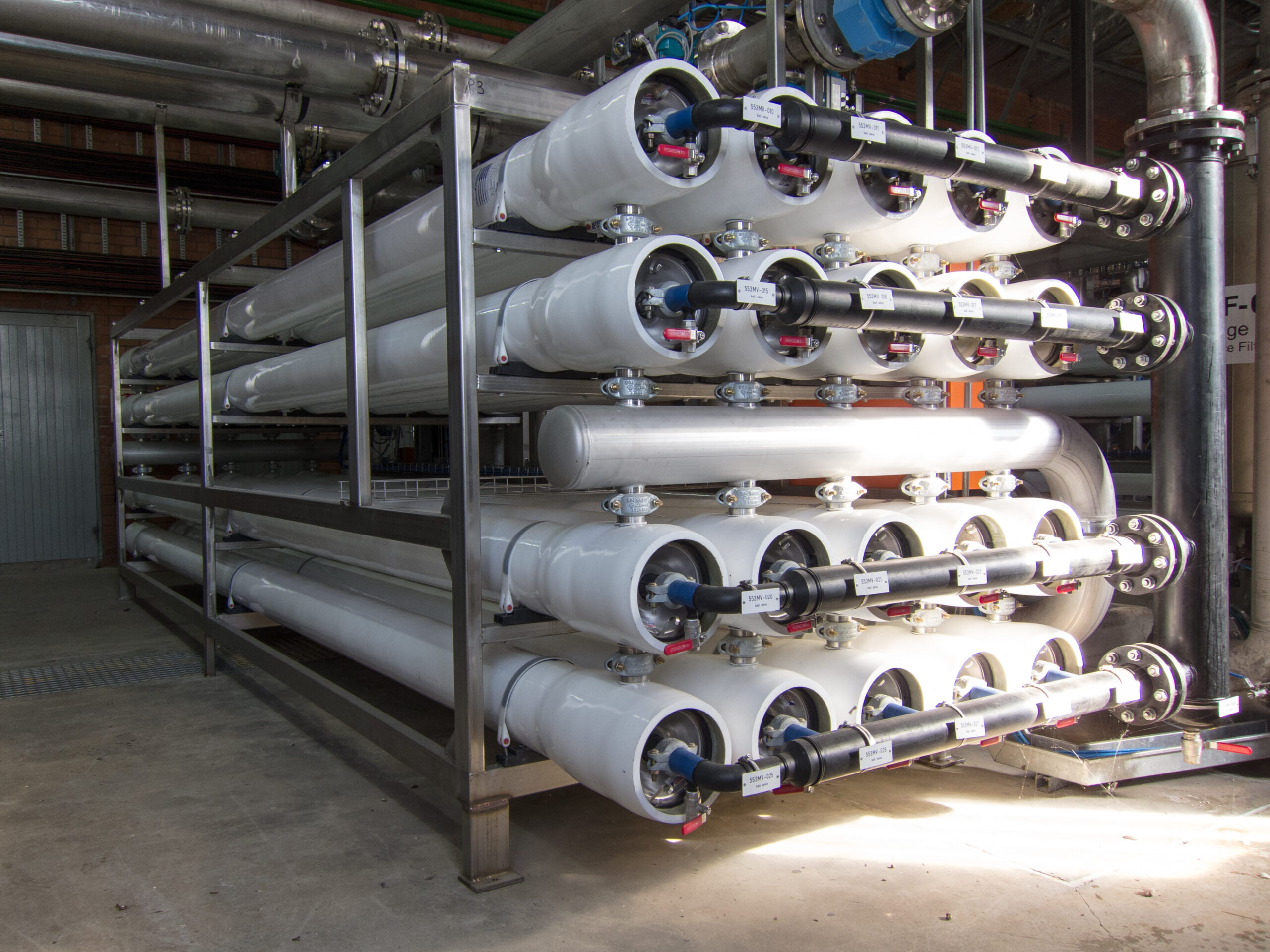 Several white pipes from a reverse osmosis system stacked on top of each other in a metal rack