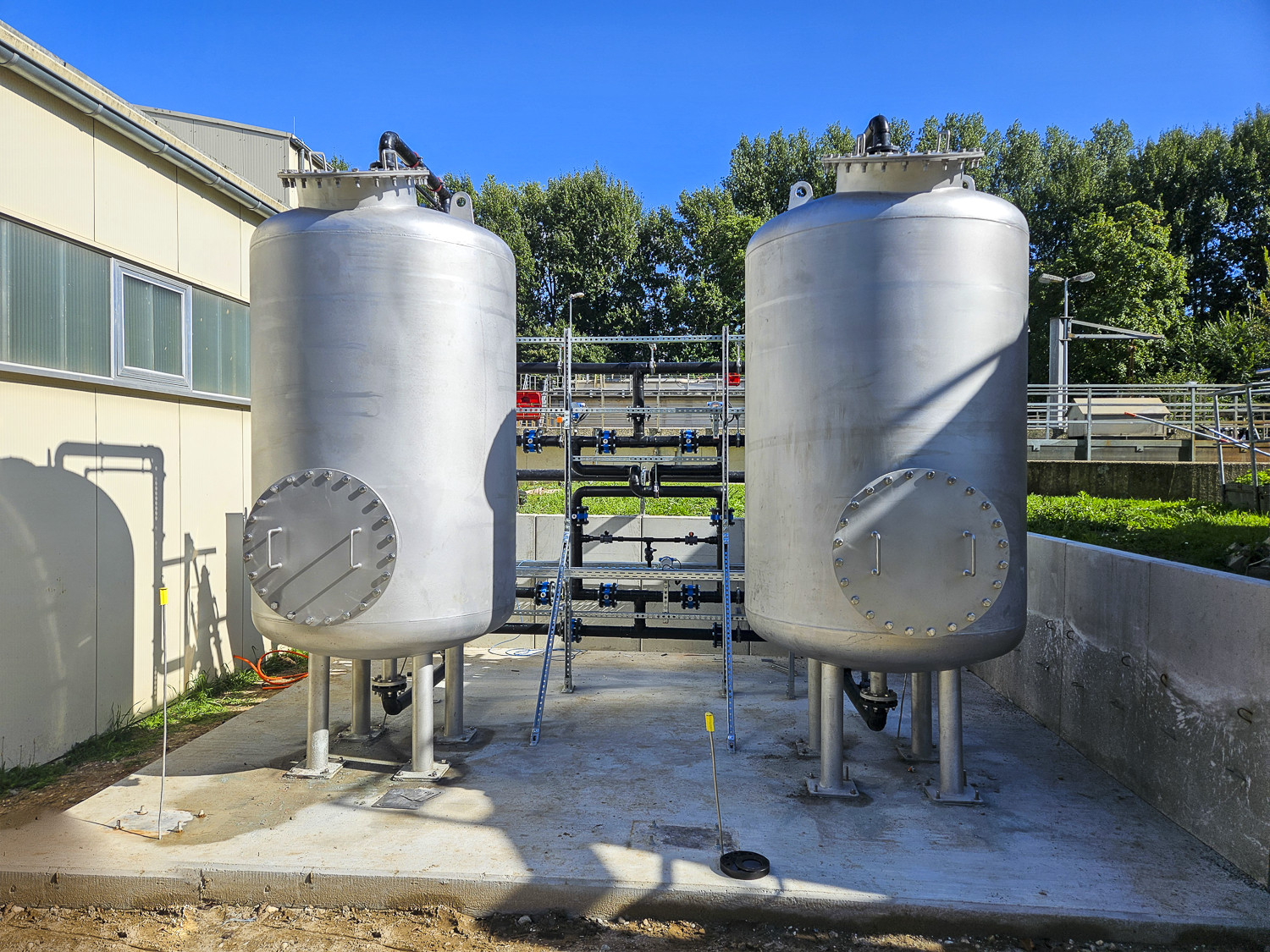 Two large, silver filtration tanks located outdoors at a facility.
