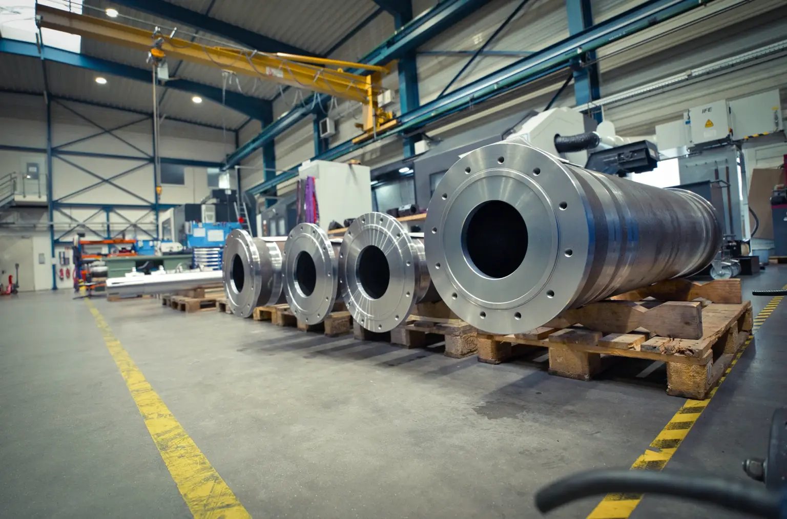 Large metal cylinders on pallets in a workshop for CNC machining of large parts.