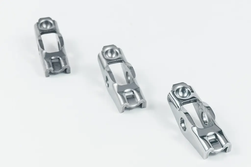Three shiny metal parts on a white background after vibratory finishing.