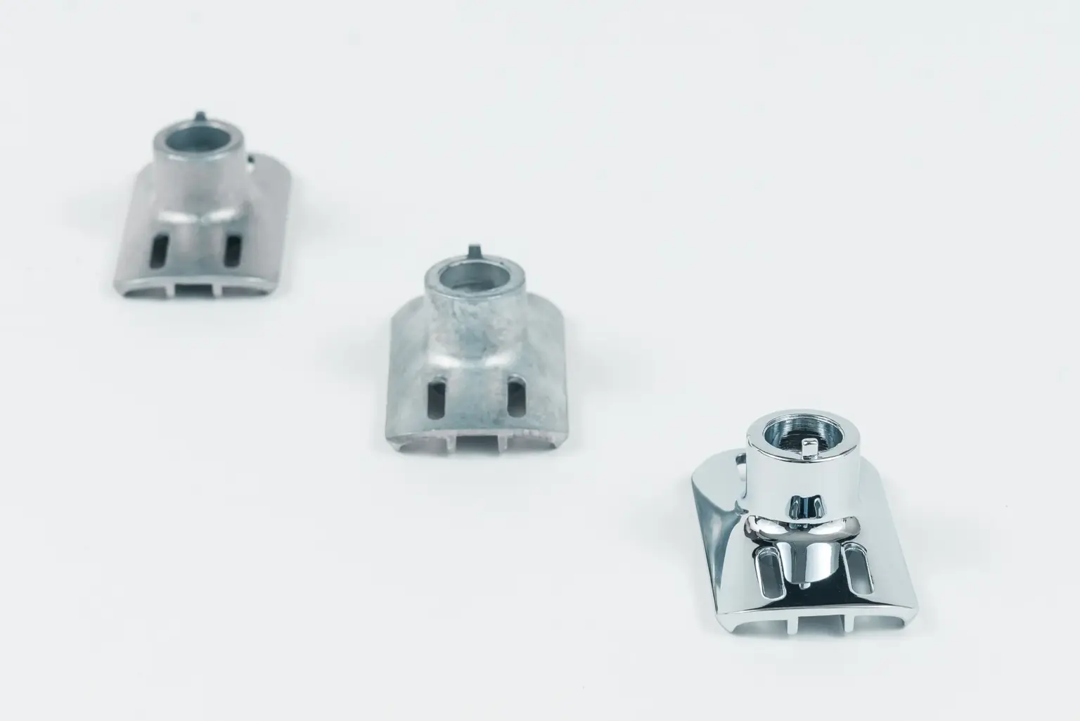 Three metal components at various stages of finishing.