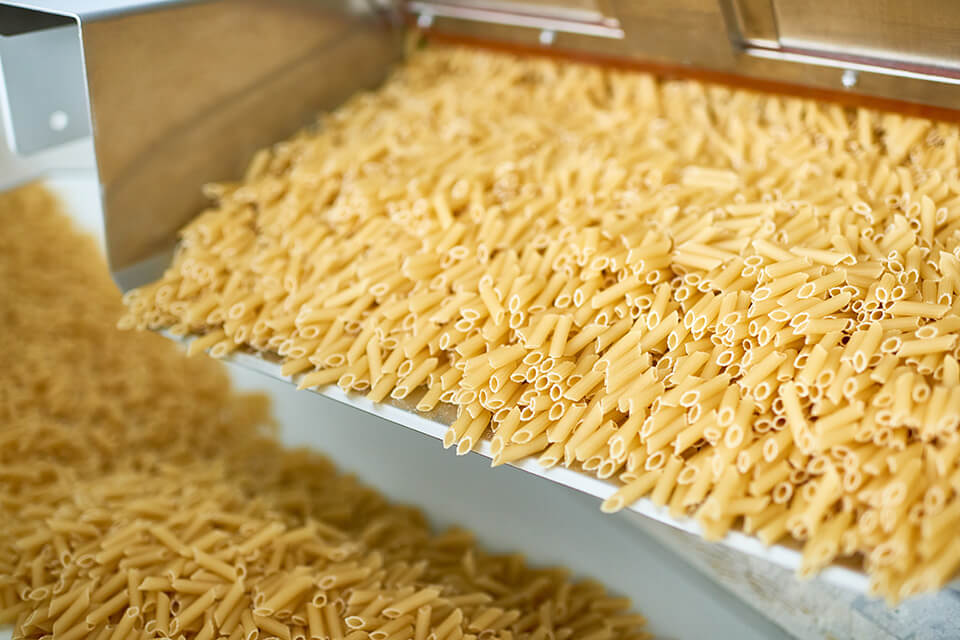 Pasta on a vibrating conveyor in a production line.