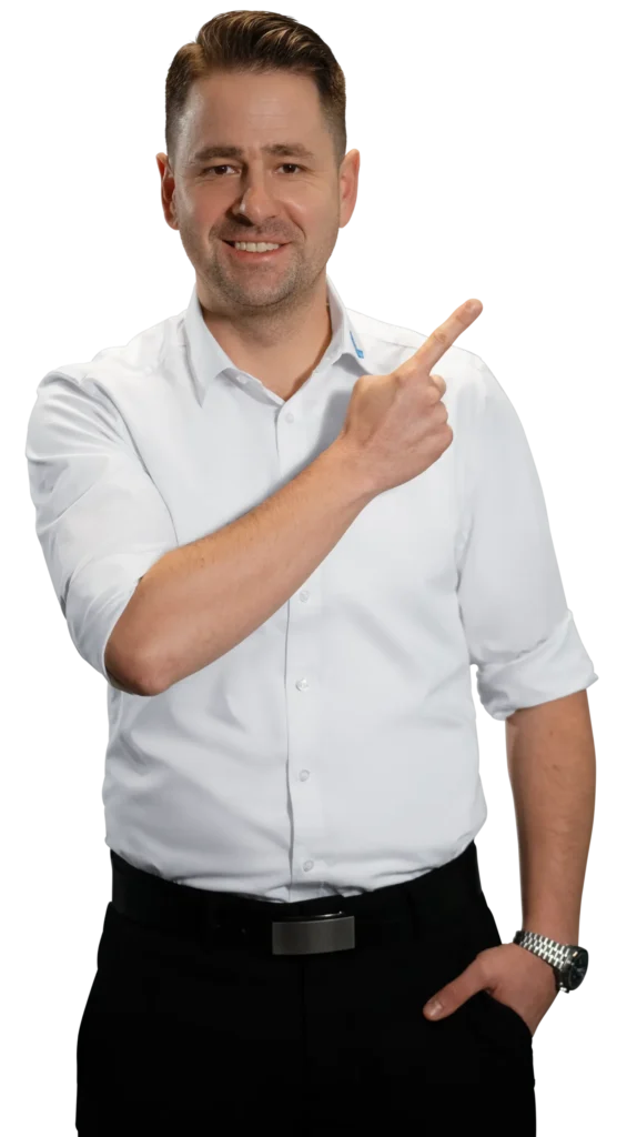 A man in a white shirt is smiling and pointing to the side.