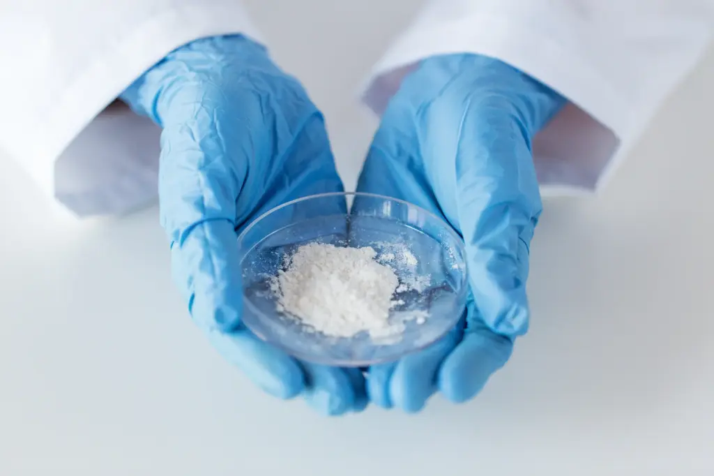 Close-up of a Petri dish containing white powder, held by two hands wearing protective gloves—used as a symbolic image for chemical products