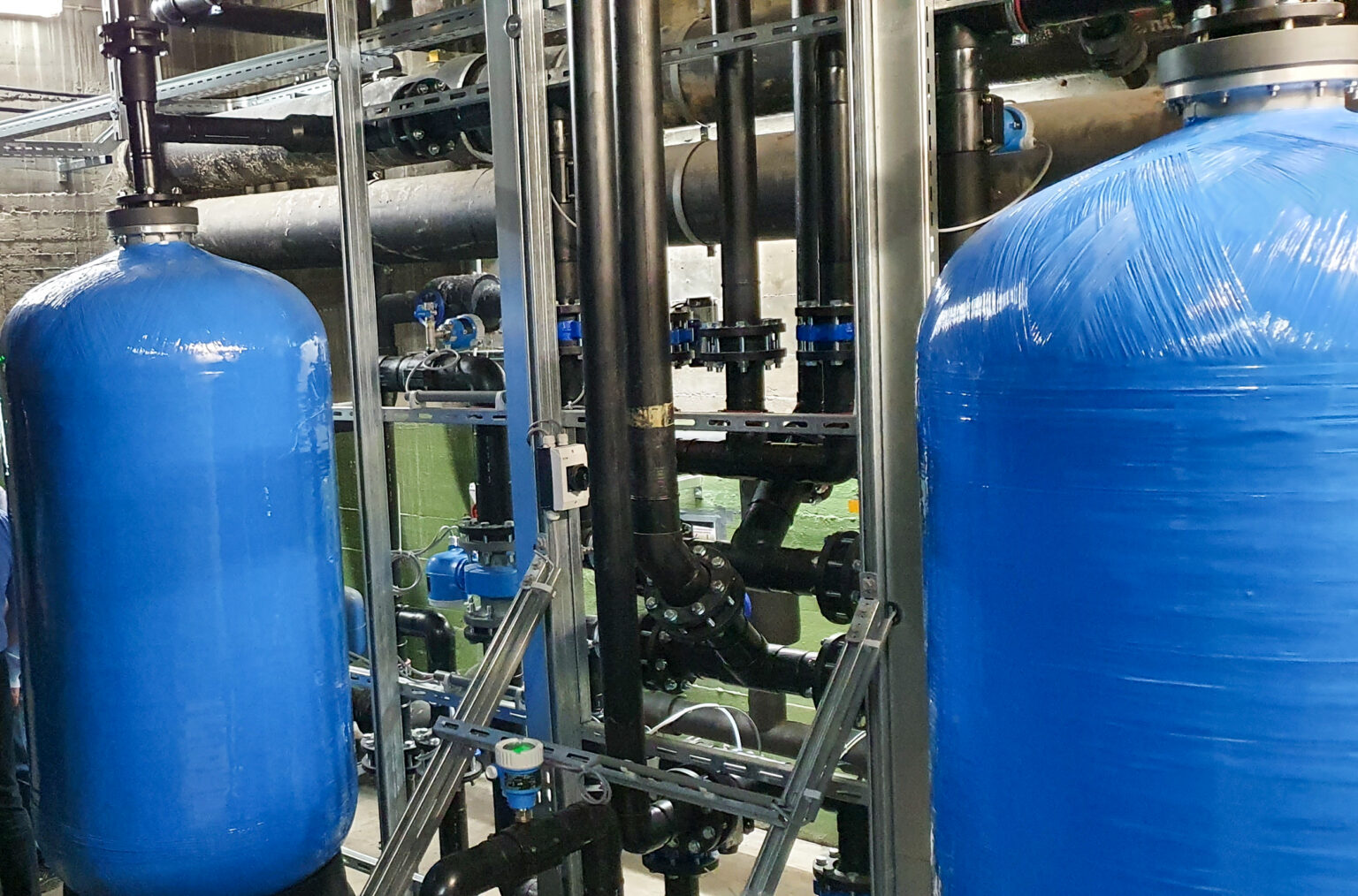 Sand filtration system with two blue tanks and piping for industrial water treatment.