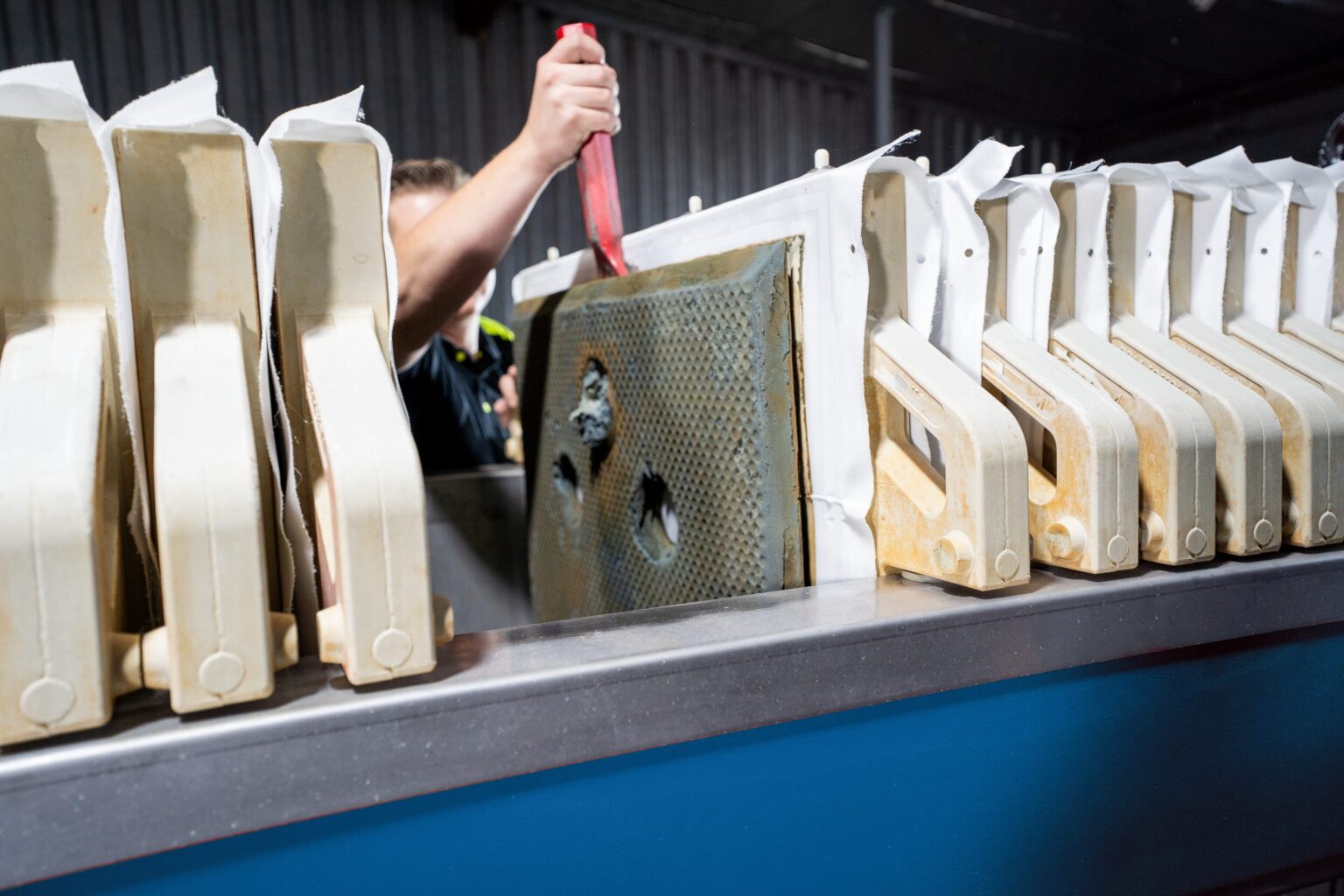 An employee removes the filter cakes from a chamber filter press.