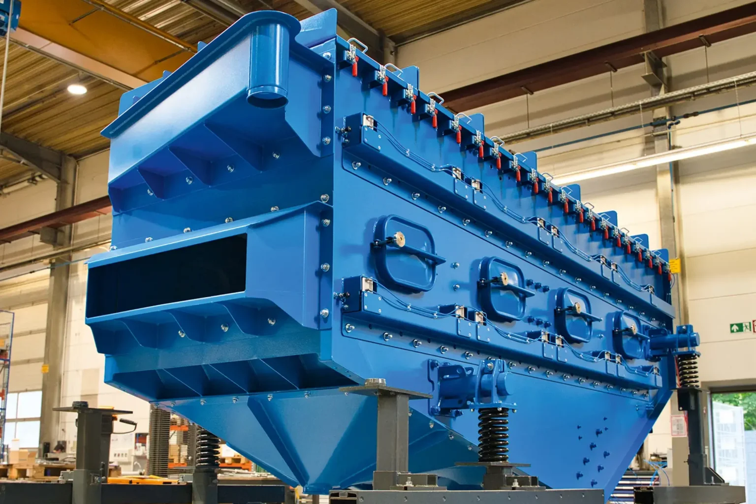 A large blue metal machine in a factory, suitable for SURFACE TREATMENT.