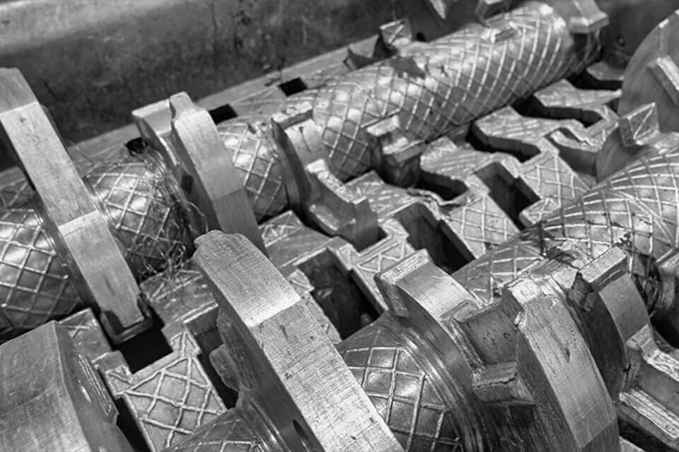 Close-up of metal rollers in a screening machine used for metal recycling.