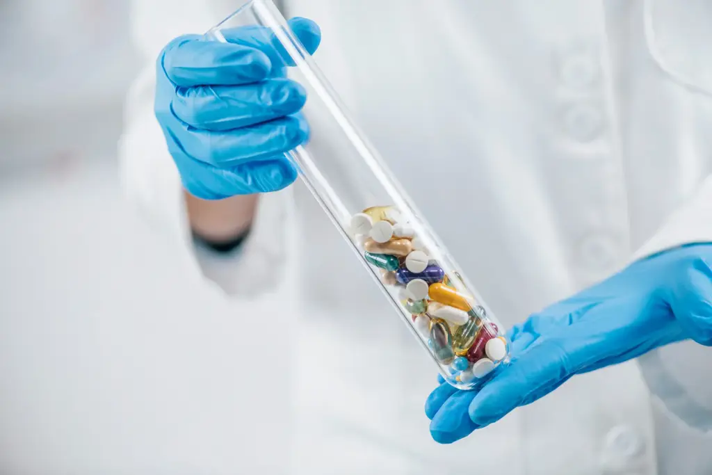An employee holds a test tube containing various pills—a symbolic image representing the pharmaceutical industry
